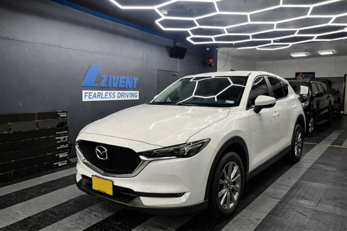 Vehículo Mazda blanco con polarizado nanocerámico Zivent instalado, ofreciendo protección solar, reducción de calor y acabado elegante en taller especializado.